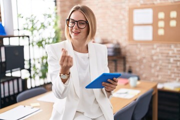 Young caucasian woman working at the office wearing glasses doing money gesture with hands, asking for salary payment, millionaire business