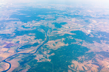 Aerial view from airplane window above green ground. View from the airplane window with beautiful clouds at sunrise