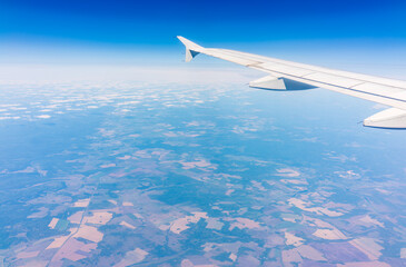 Aerial view from airplane window above green ground. View from the airplane window with beautiful clouds at sunrise