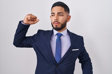 Young hispanic man wearing business suit and tie stretching back, tired and relaxed, sleepy and yawning for early morning