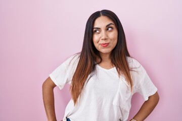 Fototapeta premium Young arab woman standing over pink background smiling looking to the side and staring away thinking.