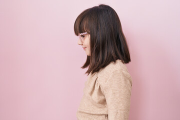 Little hispanic girl wearing glasses looking to side, relax profile pose with natural face with confident smile.