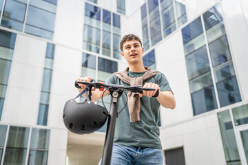 Young man caucasian teenager with electric kick push scooter in city