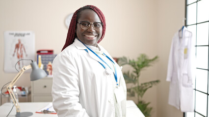 African woman with braided hair doctor smiling confident standing at clinic