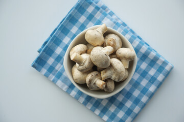 Fresh champignons mushroom in a white bowl on table 