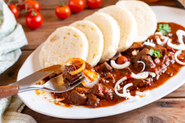 Beef goulash and dumplings (knedliky) on plate from Czech Republic. Hungarian traditional meal. Traditional Czech dish