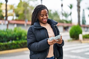 African american woman smiling confident counting dollars at street