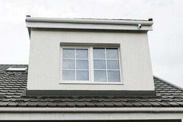 Stylish building with unfinished facade, white windows, modern black roof and dormer. Modern new...
