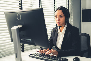 Competent female operator working on computer and talking with clients. Concept relevant to both...