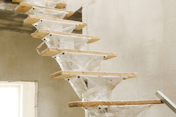 Unfinished wooden stairs to second floor in new building. Construction of house and home renovation...