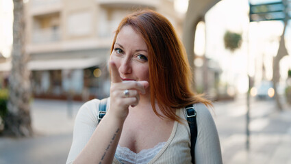 Fototapeta premium Young redhead woman smiling confident pointing with finger at street