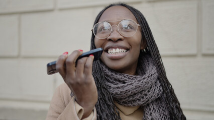 African woman sending voice message with phone at street