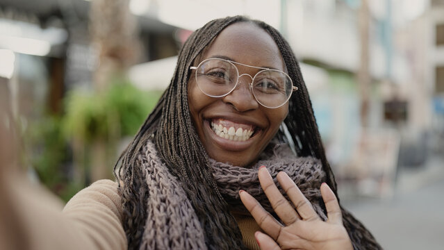 African woman taking selfie waving to the camera at street