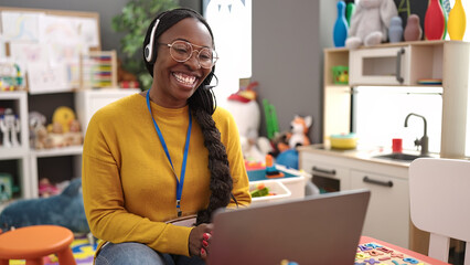 African woman preschool teacher on a video call using headset at kindergarten