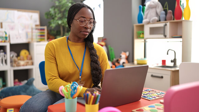 African woman preschool teacher using laptop at kindergarten - Powered by Adobe
