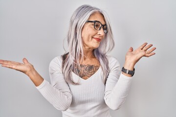 Middle age woman with grey hair standing over white background smiling showing both hands open palms, presenting and advertising comparison and balance