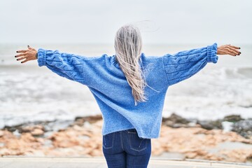 Middle age grey-haired woman standing with arms open at seaside © Krakenimages.com