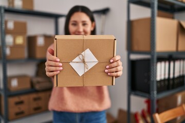 Young hispanic woman ecommerce business worker holding package at office