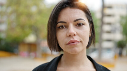 Young caucasian woman standing with serious expression at park