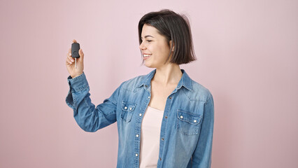 Young caucasian woman smiling confident holding key of new car over isolated pink background