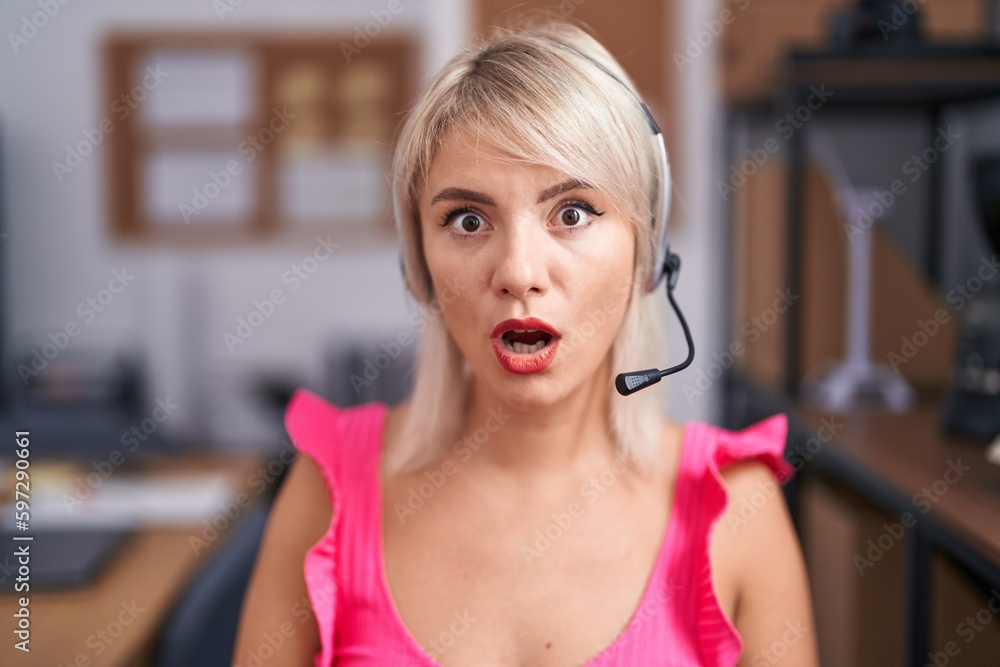 Poster Young caucasian woman wearing call center agent headset scared and amazed with open mouth for surprise, disbelief face