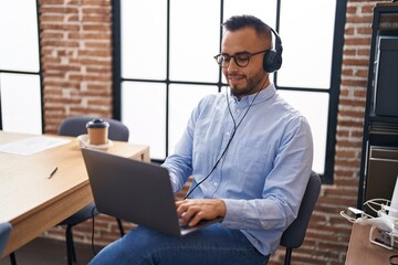 Young hispanic man business worker using laptop and headphones at office