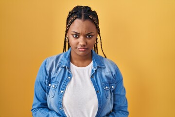 African american woman with braids standing over yellow background skeptic and nervous, frowning upset because of problem. negative person.