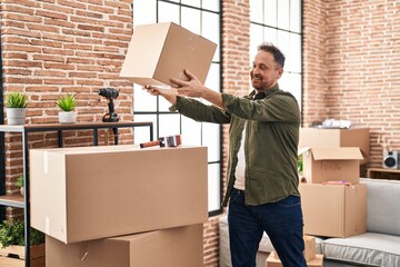 Young caucasian man smiling confident holding package at new home