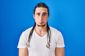 Hispanic man with long hair standing over blue background depressed and worry for distress, crying angry and afraid. sad expression.