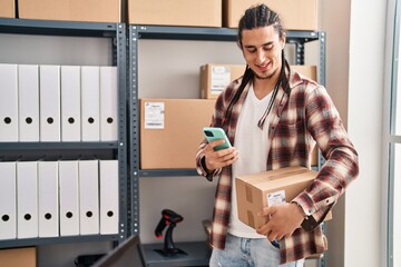 Young man ecommerce business worker using smartphone and holding package at office