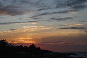 Espectacular atardecer con nubes en cielo dorado en la playa