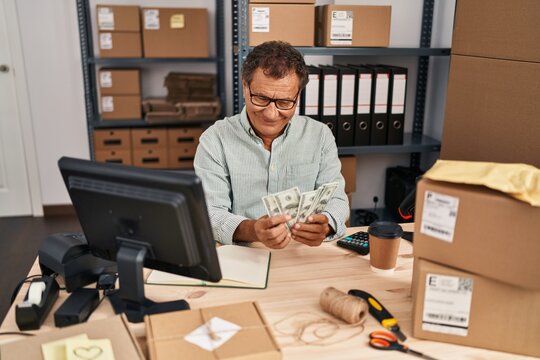 Middle age man ecommerce business worker holding dollars at office