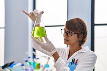 Young beautiful hispanic woman scientist holding test tube at laboratory