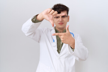 Naklejka premium Young non binary man wearing doctor uniform and stethoscope smiling making frame with hands and fingers with happy face. creativity and photography concept.