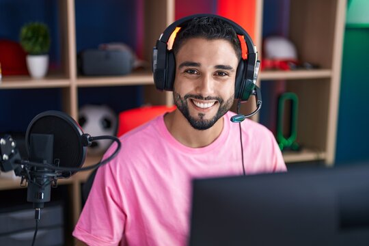 Young arab man streamer smiling confident sitting on table at gaming room