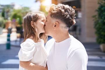 Father and daughter standing together kissing at street
