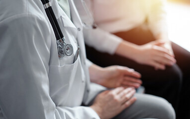 Doctor and patient discussing current health examination while sitting at the desk in clinic...