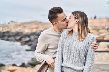 Man and woman couple hugging each other kissing at seaside