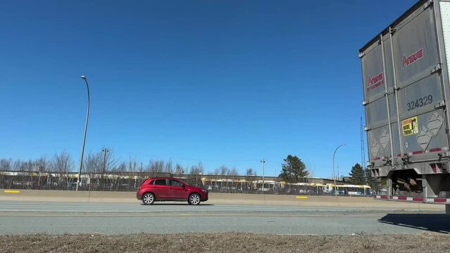 Semi-truck passes a camera on a busy highway exiting Halifax, Canada. big semi trailer with cargo trailer moving on road with cars, low view angle. 
