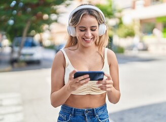 Young blonde woman smiling confident watching video on smartphone at street