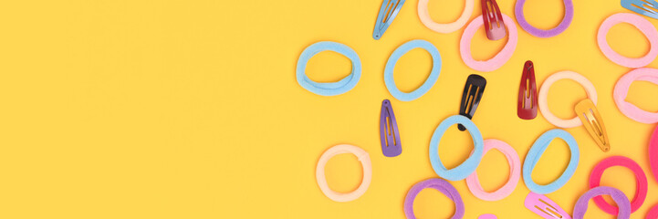 Banner with small multicolored hair scrunchies and clips on a yellow background. Place for your design.
