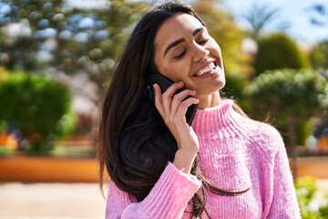 Young hispanic woman smiling confident talking on the smartphone at park