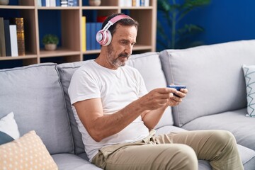 Obraz premium Middle age man playing video game sitting on sofa at home
