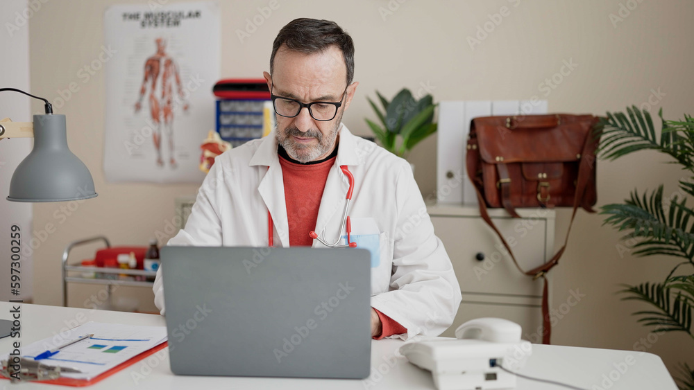 Sticker middle age man doctor using laptop working at clinic