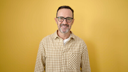 Fototapeta premium Middle age man smiling confident wearing glasses over isolated yellow background