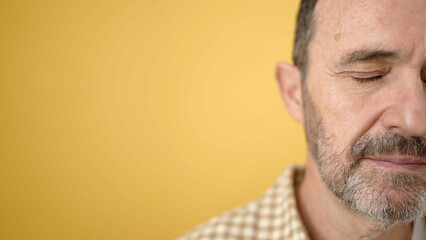 Middle age man with serious expression over isolated yellow background