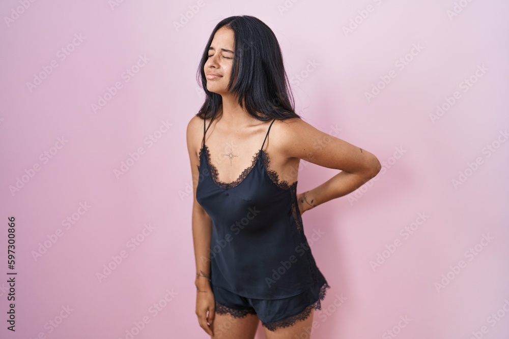 Sticker brunette woman wearing black pajama suffering of backache, touching back with hand, muscular pain