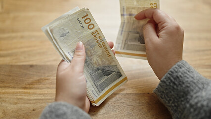 Hands of woman counting hundred denmark krone banknotes at room