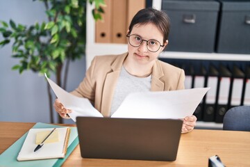 Young woman with down syndrome business worker reading document working at office