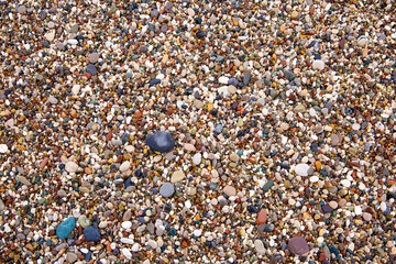 Wet rocky beach. Background. Top view. Multi-colored pebbles on the beach of the mediterranean sea. Wide photo. Turkiye, Antalya.